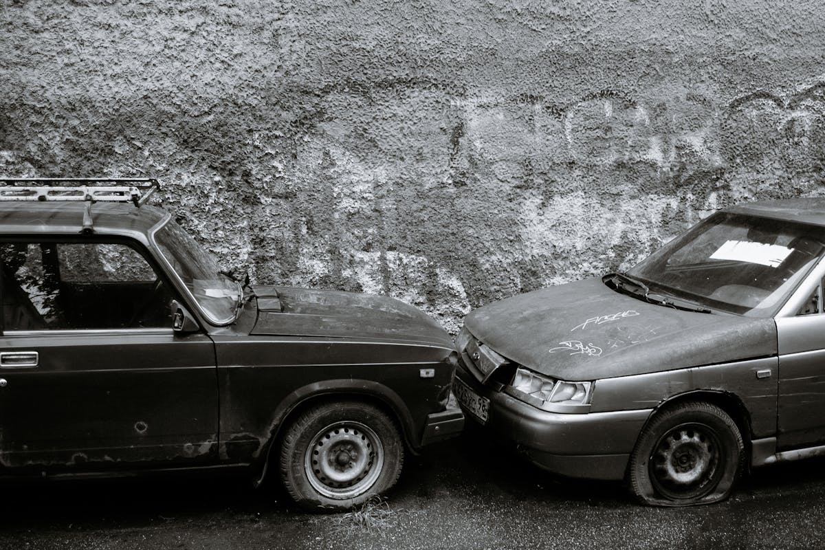 Old damaged cars near rough gray wall
